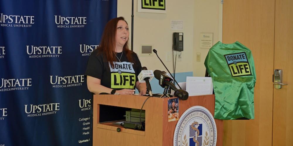 RAISING AWARENESS:  Gina Richardson, whose son Ty’Sean was struck and killed by a car in December 2022, speaks at an Upstate Donate Life awareness event April 19 urging people to sign up to be organ donors. She said her son loved superheroes and became one as his organ and tissue donation benefitted the lives or more than a dozen people. The green superhero cape on the podium is now given to parents of pediatric donors in a nod to Ty’Sean’s family’s decision to donate.